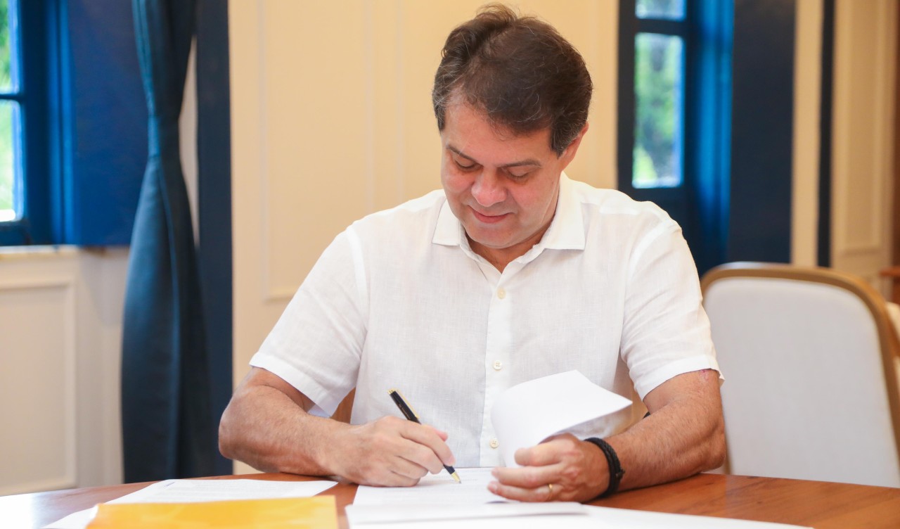 prefeito Evandro assinando um documento em seu gabinete